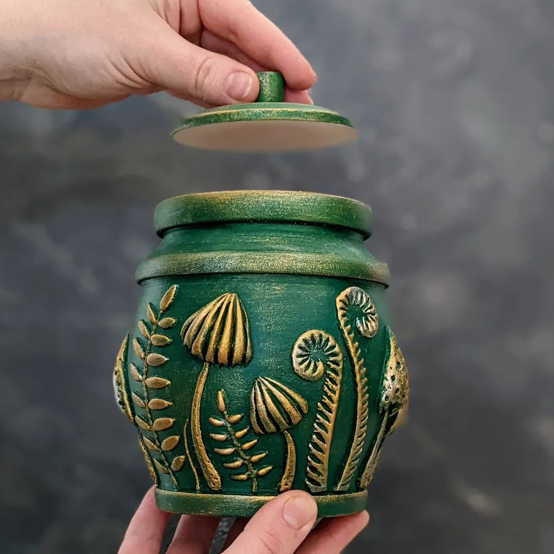 amanita mushroom emeral green pot in hands with the lid open  