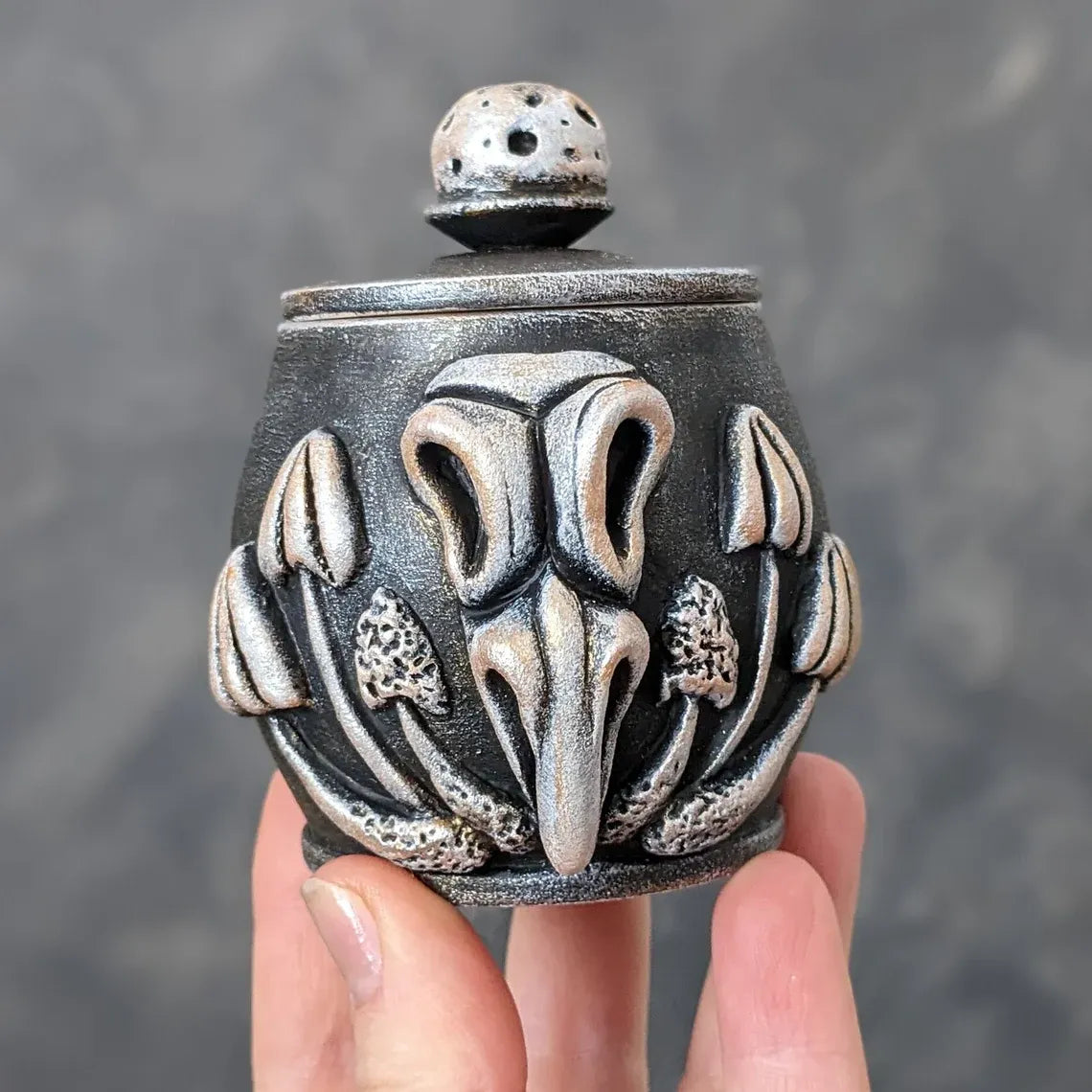 crow skull with mushrooms wooden pot with lid in hand