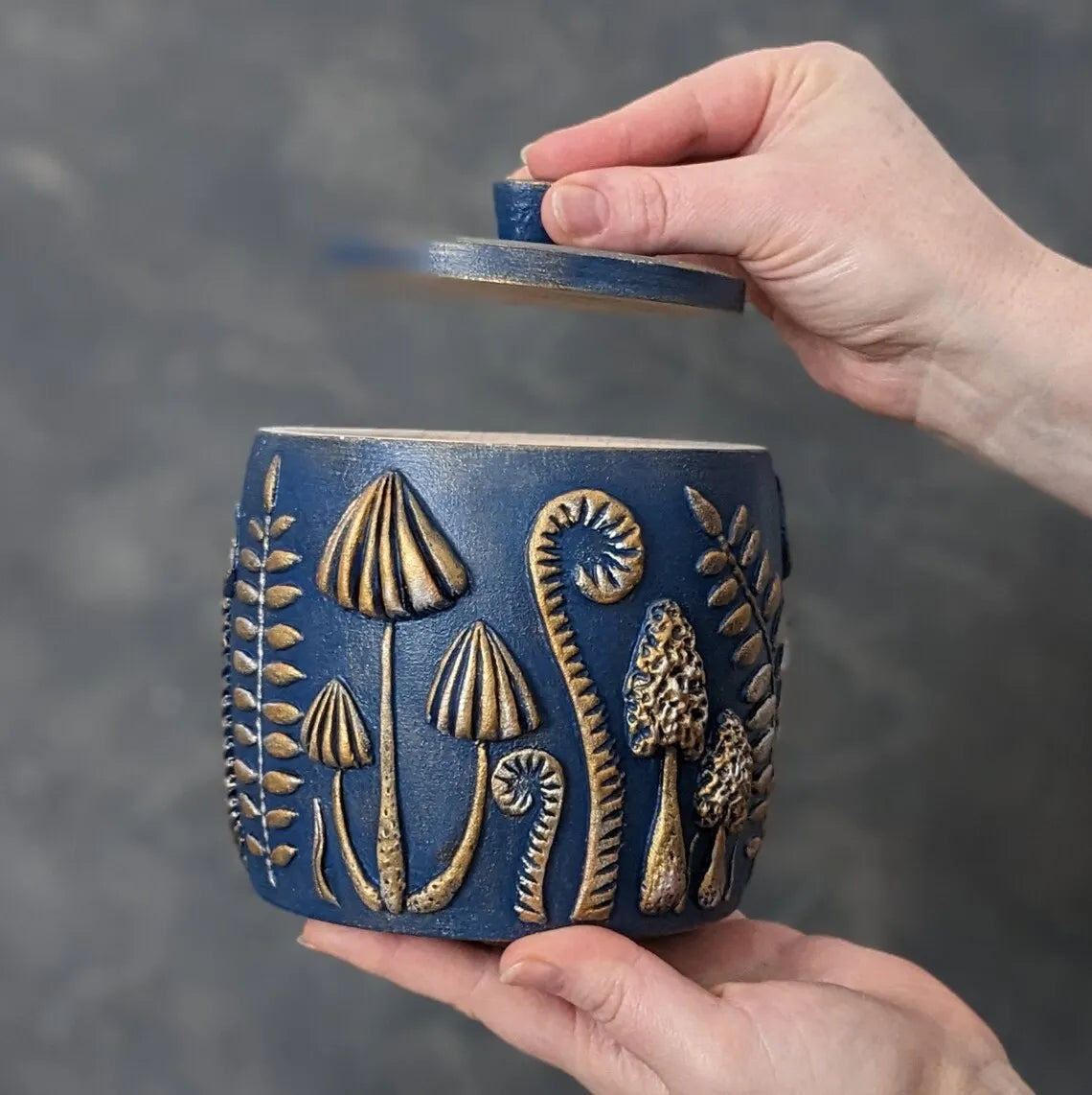 forest herbs and mushrooms blue wooden pot with lid in hands