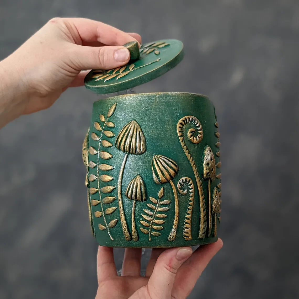 forest herbs and mushrooms emerald green wooden pot with lid in hand 