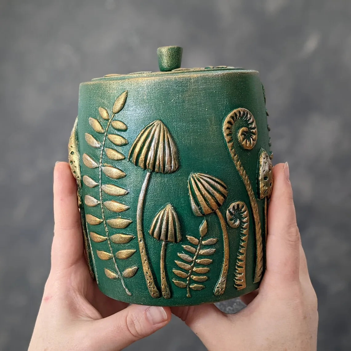 forest herbs and mushrooms emerald green wooden pot with lid in hands